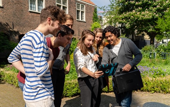 Een groep deelnemers bespreekt een opdracht op de iPad
